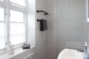 baño de azulejos blancos con lavabo y ventana en Stadthaus Jürgensby, en Flensburg