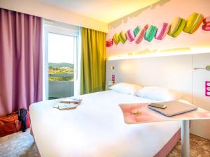 um quarto com uma cama branca e um computador portátil sobre uma mesa em ibis Styles Fréjus St Raphael em Fréjus