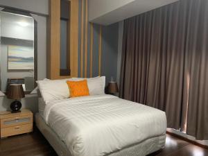 een slaapkamer met een bed met een oranje kussen erop bij AEON SUITES STAYCATION managed by ARIA HOTEL in Davao City