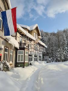 a building with a flag in the snow at Hotel Zur Luppbode in Treseburg