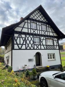 una casa bianca e nera con una macchina parcheggiata di fronte di Ferienwohnung Hesselbach a Oberkirch