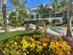 um grande edifício com palmeiras e um jardim em Atmospheric apartment with a beautiful view of the swimming pool em Bayahibe