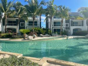 uma piscina com palmeiras em frente a um edifício em Atmospheric apartment with a beautiful view of the swimming pool em Bayahibe