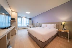 a hotel room with a large bed and a television at SureStay Plus Hotel by Best Western Asan in Asan