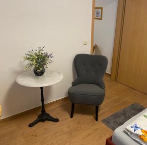 una habitación con una silla y una mesa con un jarrón de flores en Ferienwohnung Zentrum, en Neuruppin