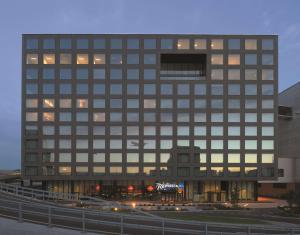 een hoog gebouw met een bord ervoor bij Radisson Blu Hotel Zurich Airport in Kloten