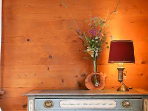 una mesa con una lámpara y un jarrón de flores. en Chalet Chalet Merymont by Interhome, en Villars-sur-Ollon