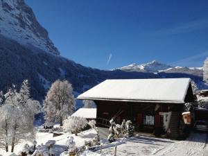 un edificio ricoperto di neve con montagne sullo sfondo di Apartment Chalet Bärgsunna-4 by Interhome a Grindelwald