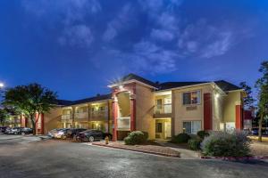 a hotel with cars parked in front of a parking lot at Suburban Studios in Albuquerque