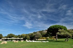 un grupo de personas sentadas en un campo con sombrillas en Bagaglino I Giardini Di Porto Cervo, en Porto Cervo