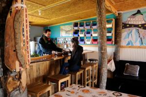 a man and a woman sitting at a bar at Camping Güino in Puerto Natales