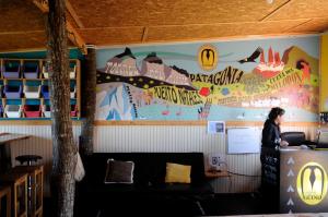 a woman standing in a room with a mural on the wall at Camping Güino in Puerto Natales