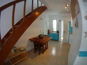 cocina y comedor con mesa de madera y escaleras en Ahoy Porto Covo Hostel, en Porto Covo