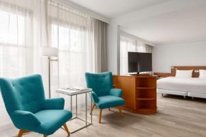 a hotel room with two chairs and a tv and a bed at NH Bussum Jan Tabak in Bussum