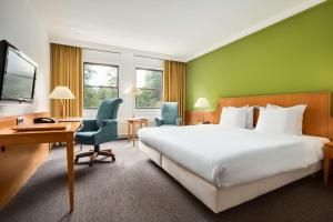 a hotel room with a large bed and a desk at NH Bussum Jan Tabak in Bussum