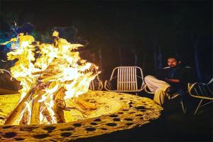 un homme fumant une cigarette à côté d'un feu dans l'établissement Mountain Breeze Resort, Mahabaleshwar, à Mahabaleshwar