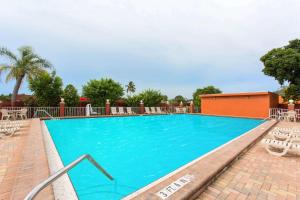 una gran piscina azul con sillas y árboles en Days Inn by Wyndham Fort Myers, en Fort Myers