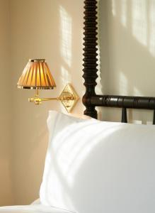 een lamp naast een bed met een wit kussen bij The Ludlow Hotel in New York