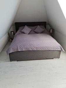 a bedroom with a bed with purple comforter and two lamps at Apartamenty Platinum in Łukęcin