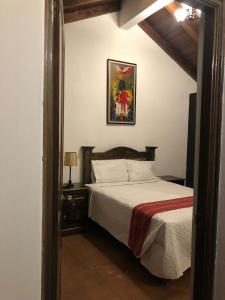 - une chambre avec un lit et une photo sur le mur dans l'établissement Hotel Mansion Del Rey, à Antigua Guatemala