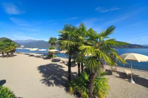 una playa con palmeras y sombrillas junto al agua en Hotel Splendid, en Baveno