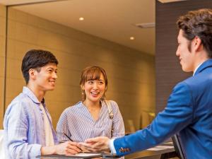 Un gruppo di tre persone che si trovano intorno a un tavolo con un uomo di Comfort Hotel Nagoya Kanayama a Nagoya