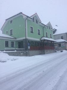 een groot groen gebouw met sneeuw op de grond bij Penzion U Pešků in Horní Planá