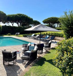 een groep stoelen en een parasol naast een zwembad bij Gallia Palace Hotel - Relais & Châteaux in Punta Ala