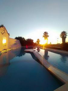 a swimming pool with the sunset in the background at Turim Club Azeitao Hotel in Setúbal