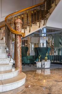 eine Lobby mit einer Wendeltreppe und grünen Stühlen in der Unterkunft Radisson Blu Hotel Schwarzer Bock Wiesbaden in Wiesbaden