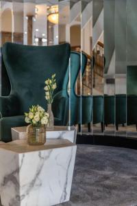 eine Lobby mit einem grünen Stuhl und einem Tisch mit Blumen in der Unterkunft Radisson Blu Hotel Schwarzer Bock Wiesbaden in Wiesbaden