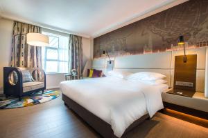 een slaapkamer met een groot wit bed en een stoel bij Radisson Blu Hotel, Antwerp City Centre in Antwerpen