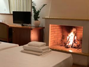 a fireplace in a room with a bed and a television at Corinthian Village in Vrahati