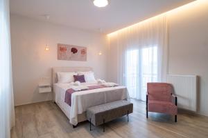 una camera bianca con un letto e una sedia di Lux Palace Trikala a Tríkala