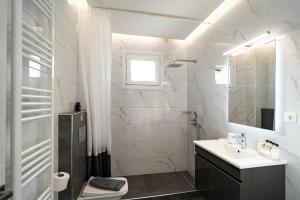 bagno bianco con lavandino e specchio di Lux Palace Trikala a Tríkala