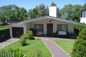 uma pequena casa branca com um jardim de relva em Casa Simona Villa General Belgrano em Villa General Belgrano