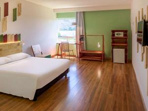 a bedroom with a bed and a wooden floor at Hotel Nacional Inn Curitiba Santa Felicidade in Curitiba