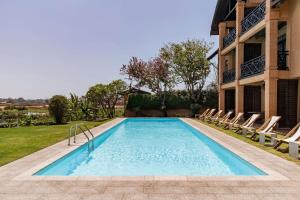 uma piscina num quintal com cadeiras e um edifício em Radisson Hotel Tamboho Waterfront Antananarivo em Antananarivo