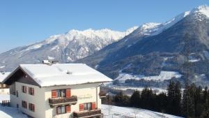 um edifício na neve com montanhas ao fundo em Jugend- und Familienhotel Venedigerhof em Neukirchen am Großvenediger