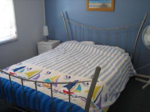 a bed in a bedroom with a blue wall at Horace Street 8 in Shoal Bay