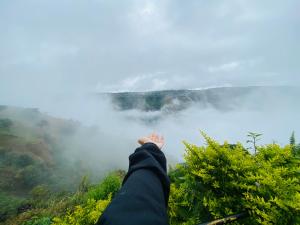 una persona sobresaliendo de la cima de una montaña en Lifeline Villas - Miracle 5BHK Infinity Pool Villa With Breathtaking Valley View And Huge Lawn Area, en Mahabaleshwar