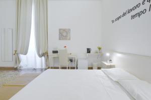 una camera bianca con un letto bianco e un tavolo di Ada Suites & Spa a Lecce