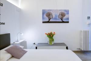 una camera con un letto bianco e un vaso di fiori di Ada Suites & Spa a Lecce