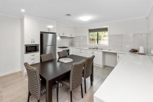 a kitchen with a table and chairs and a refrigerator at Fawkner Executive Suites & Serviced Apartments in Melbourne