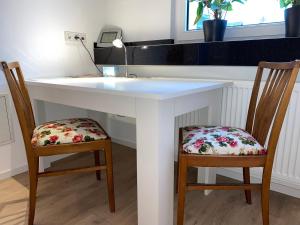 twee stoelen aan een witte tafel met een wastafel bij Home-Rose-Garden-Gästehaus kontaktloser Zugang in Düsseldorf