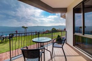 d'un balcon avec une table et des chaises et une vue sur l'eau. dans l'établissement Mountain Breeze Resort, Mahabaleshwar, à Mahabaleshwar