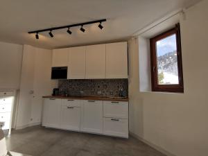 an empty kitchen with white cabinets and a window at Aura Apartment - Ski In & Ski Out - Cerviniaholidays-com in Breuil-Cervinia