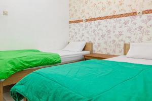 two beds in a room with green sheets at Lesehan Cahaya Tetebatu Inn Syariah at Desa Wisata in Tetebatu