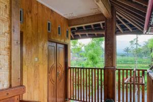 a porch of a wooden cabin with a large window at Lesehan Cahaya Tetebatu Inn Syariah at Desa Wisata in Tetebatu