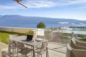 d'une table, de chaises et d'un ordinateur portable sur le balcon. dans l'établissement Relais Zenner, à Toscolano Maderno